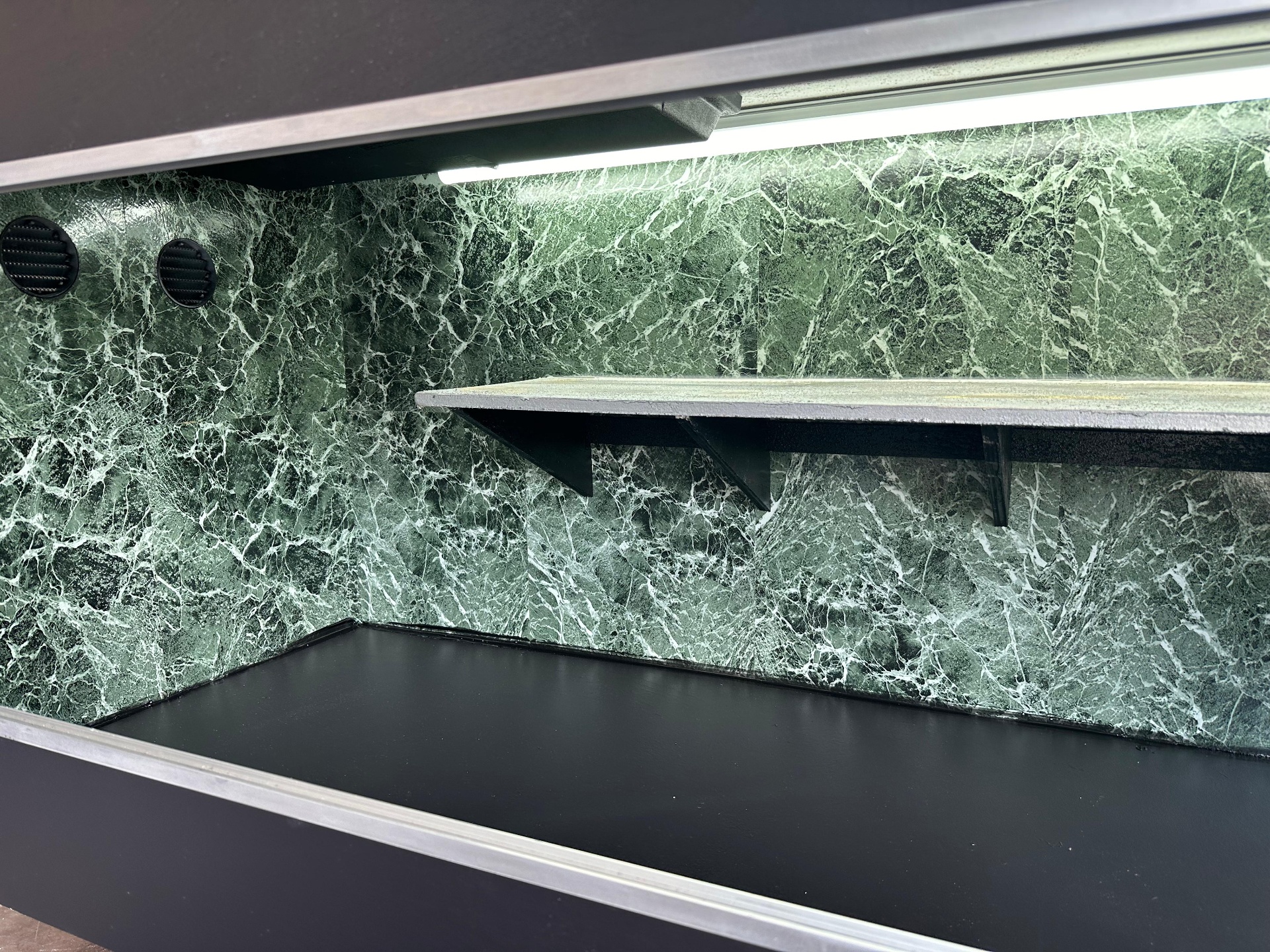 Interior of an early enclosure with green marble back panel and aluminum LED track